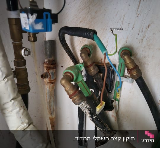 חיבורי צנרת וכבלי חשמל גלויים במערכת חימום מים